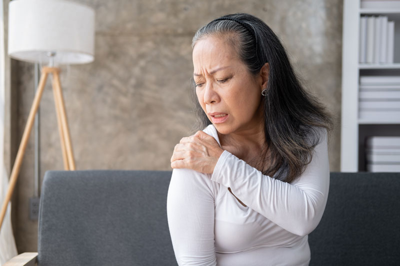 A woman suffers from shoulder pain due to osteoporosis.