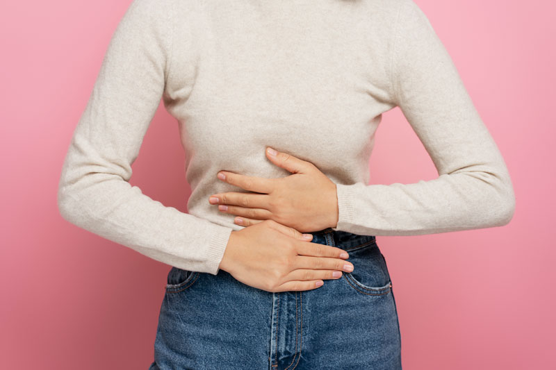 A woman with ovarian cysts holds her stomach.