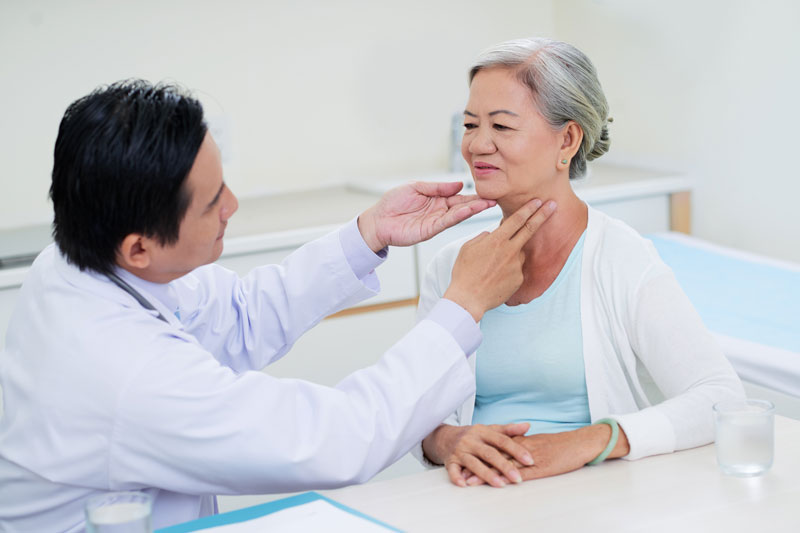 A woman receives a thyroid examine from an endocrinologist.