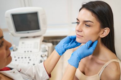 A doctor examines a young woman’s thyroid and neck.